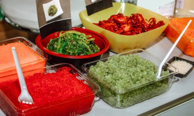 Uçan balık yumurtası, kapelin yumurtası, yosun salatası ve tek kullanımlık tabakta bebek ahtapot salatası.