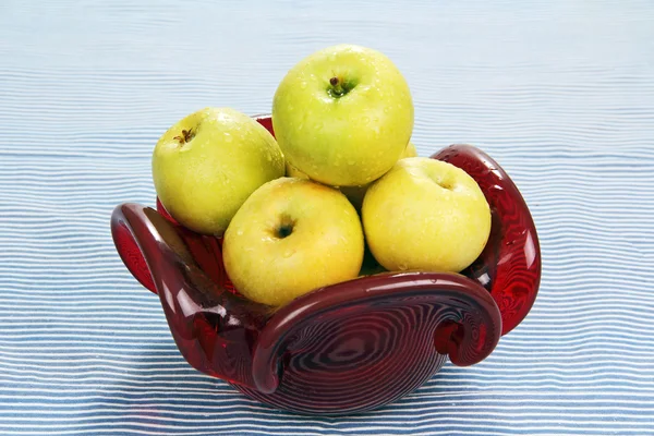 Manzanas en un jarrón de cristal rojo . — Foto de Stock