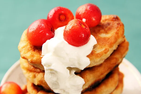 Pannenkoeken met zure room en een kers. — Stockfoto