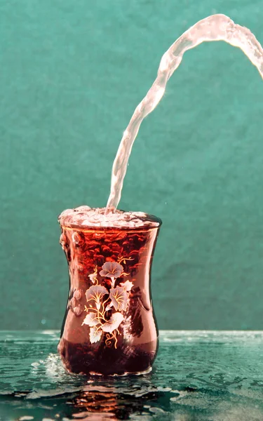 Stream of water pours into the colored glass. — Stock Photo, Image