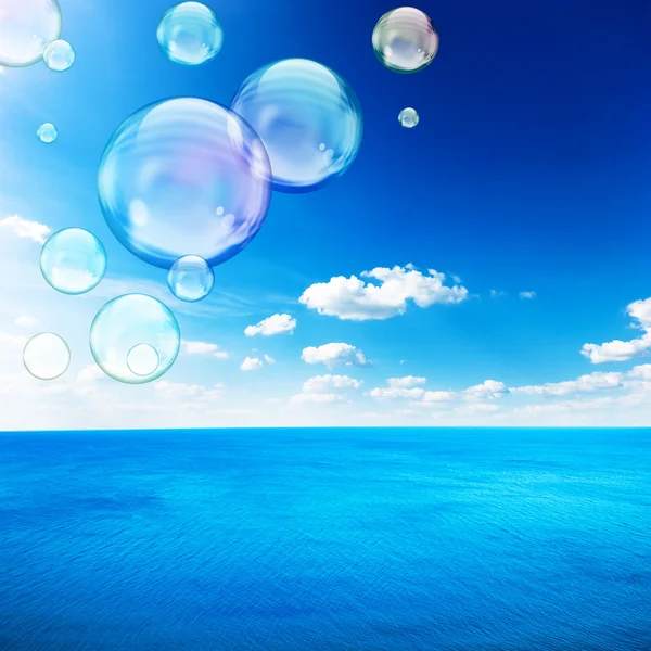 Blue sea under clouds sky with flying soap bubble — Stock Photo, Image