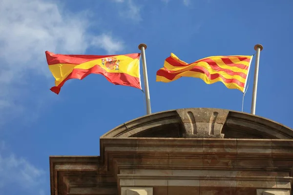 西班牙国旗和加泰罗尼亚国旗在巴塞罗那加泰罗尼亚议会山顶风中并肩作战 — 图库照片