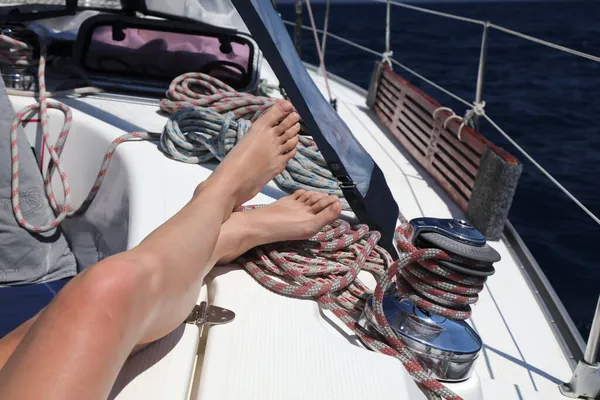 Sailing in Adriatic, Croatia. Woman sailor legs relaxed. Sailboat equipment: colorful rope on a capstan.