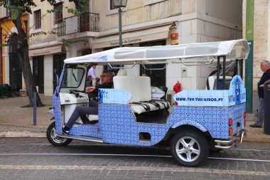 LISBON, PORTUGAL - JUNE 4, 2018: Tuk tuk city tour driver waits in Lisbon, Portugal. Lisbon is the 11th-most populous urban area in the EU (2.8 million people).