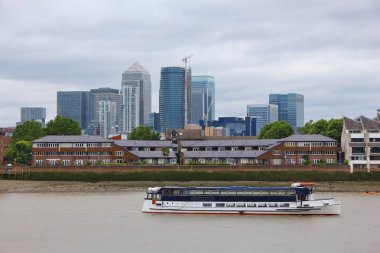 Londra 'nın Greenwich bölgesinden Canary Wharf ve London Docklands görüldü. Thames nehrinde bir tur teknesi.