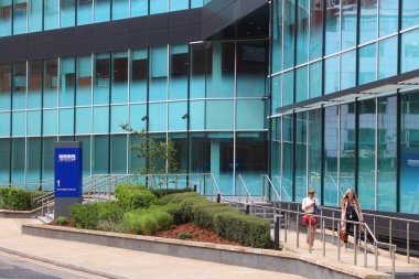 LEEDS, İngiltere - 11 Temmuz 2016: İnsanlar Leeds, İngiltere 'deki KPMG binasının önünden geçiyor. KPGM, Büyük Dörtlü denetçi şirketlerinden biri. 2013 yılında 23,4 milyar ABD Doları geliri ve 155,000 çalışanı vardı..