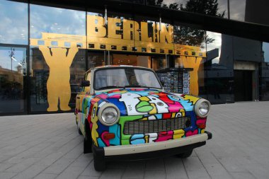 Berlin, Almanya - 25 Ağustos 2014: İnsanlar Berlin'de park etmiş Renkli Trabant 601 aracına hayran. 3,096,099 Trabant otomobili rezil verimsizliklerine ve modası geçmiş teknolojilerine rağmen üretildi.