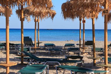 Girit Yunan adası. Elafonisi 'deki kumsal (veya Elafonissi). Güneş yatakları ve saman şemsiyeleri.
