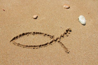 Christianity symbol - religious fish shape drawn in sand. Catholicism fish - ichthus.