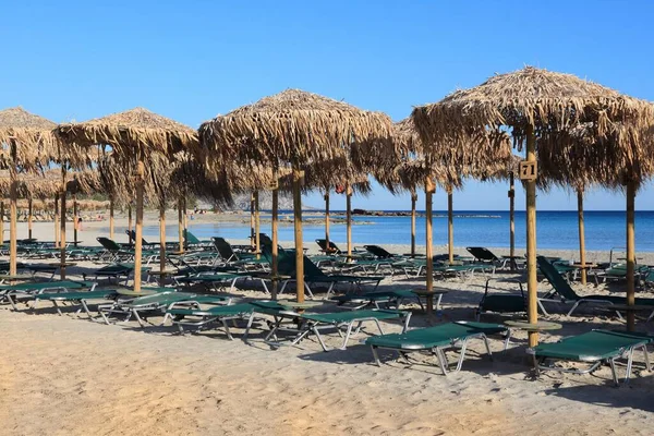 Girit Yunan adası. Elafonisi 'deki kumsal (veya Elafonissi). Güneş yatakları ve hasır şemsiyeler.