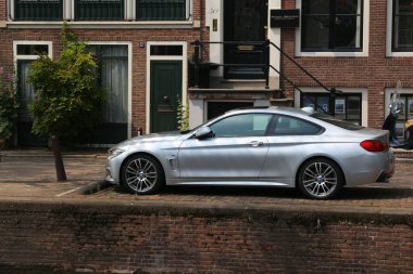 AMSTERDAM, NETHERLANDS - 7 Temmuz 2017: BMW M4 performans coupe otomobili Amsterdam 'da kanal kenarına park edildi. Hollanda 'da 1.000 kişi başına 528 kayıtlı araç var..