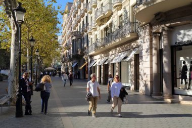 BARCELONA, İspanya - 7 Ekim 2021: İnsanlar İspanya 'nın Eixample ilçesindeki Passeig de Gracia caddesini ziyaret ediyor. Passeig de Gracia modernist mimarisi ve ana cadde moda alışverişi ile ünlüdür..