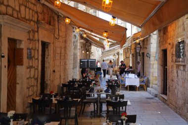 DUBROVNIK, CROATIA - JULY 18, 2021: Tourists narrow streets and shaded restaurants of medieval Dubrovnik Old Town city walls, a UNESCO World Heritage Site.