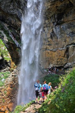 OBERTAUERN, AUSTRIA - 5 Ağustos 2022: Avusturya 'daki Tauern dağlarında Johannes Waterfall' un altındaki patikada insanlar yürüyor. Avusturya 'daki en yüksek şelalelerden biridir..