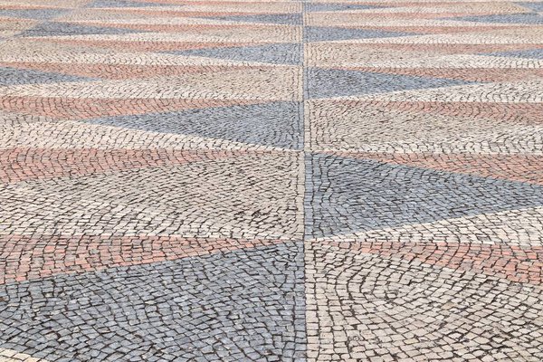 Stone paved square background - ornamental cobblestone pattern in Belem district of Lisbon city, Portugal.