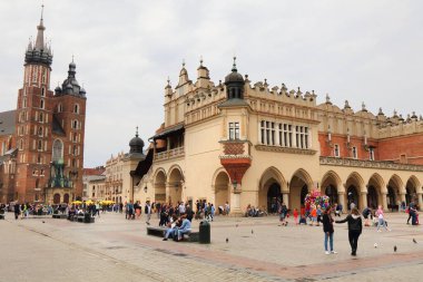 KRAKOW, POLAND - 3 Temmuz 2021: İnsanlar Krakow, Polonya 'da yağmurlu bir günde Rynek Meydanı' nı ziyaret ediyor. Krakow Tarihi Merkezi UNESCO 'nun Dünya Mirasları Alanıdır..