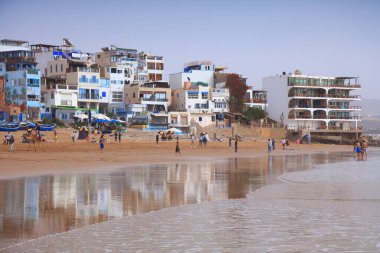 TAGHAZOut, MoroCCO - 27 Şubat 2022: İnsanlar Fas 'ın Agadir yakınlarındaki Taghazout sörf kasabasındaki plajı ziyaret ediyor.