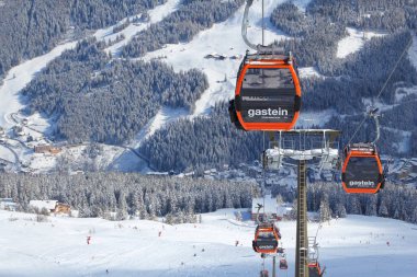 BAD GASTEIN, AUSTRIA - MARCH 9, 2016: People ride gondolas of cable car in Bad Gastein. It is part of Ski Amade, one of largest ski regions in Europe with 760km of ski runs. clipart