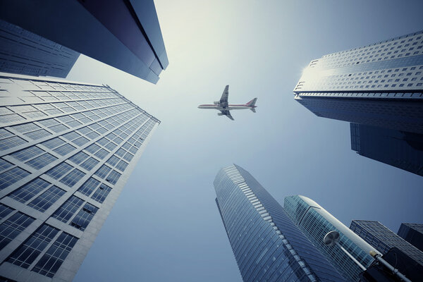 Looking up at aircraft flying over the modern urban office buildings backgrounds at Shangha