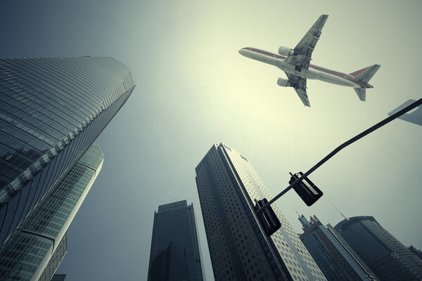 Looking up at aircraft flying over the modern urban office buildings backgrounds at Shangha