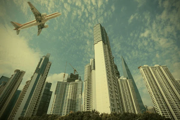 Aircraft flying over the modern city buildings — Stock Photo, Image