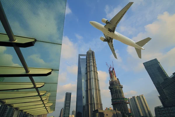 Aircraft flying over the modern city buildings over — Stock Photo, Image