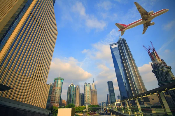 Modern şehir binaları üzerinde üzerinde uçan uçak — Stok fotoğraf