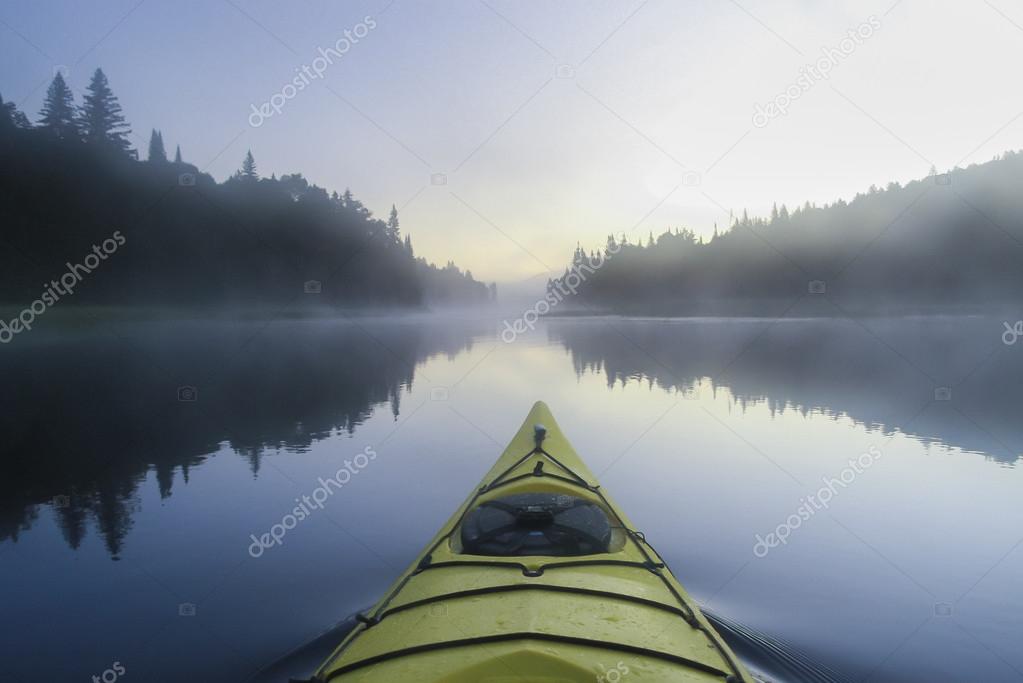 Kayak surfer on a misty lake