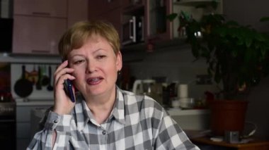 Kahverengi saçlı ve kareli gömlekli olgun bir kadın telefona cevap verir ve iyi haberlerle çok mutlu olur, mutluluk şarkısı söyler, elini kaldırır ve evet der. İçeride. Portre.