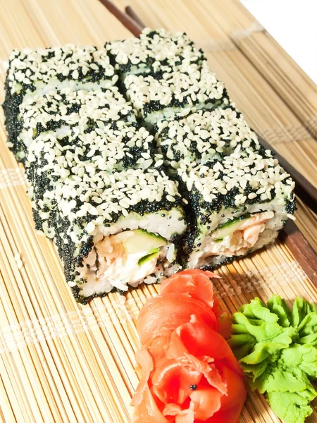 Rollos de sushi con huevas negras y sésamo en estera de bambú —  Fotos de Stock
