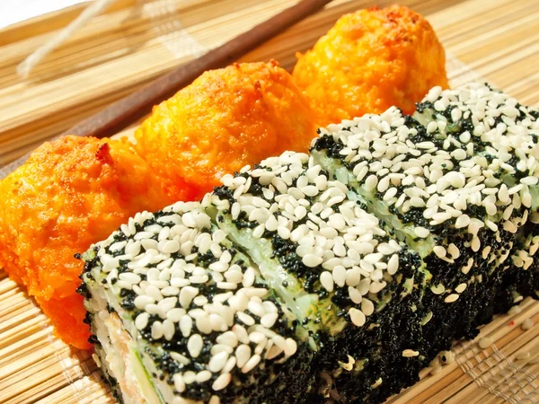 Rolls with black roe and sesame and baking sushi on bamboo mat — Stock Photo, Image