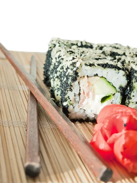 Rollos de sushi con huevas negras y sésamo en estera de bambú — Foto de Stock