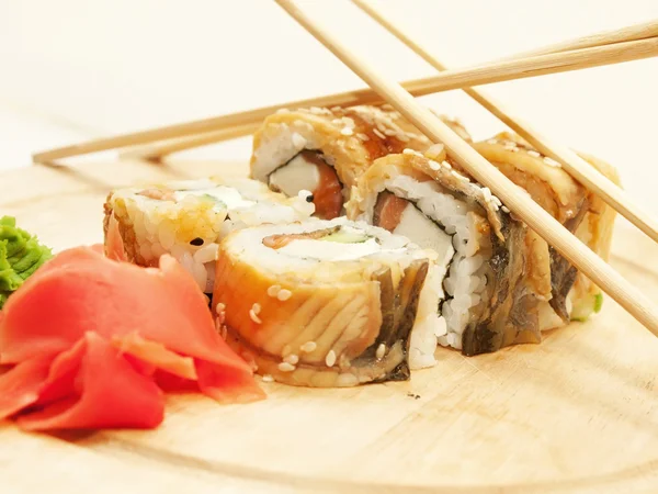 Rouleaux de sushi avec omelette et anguille et baguettes sur le bureau gros plan — Photo