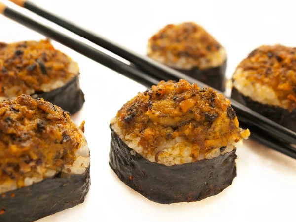 Baked sushi rolls with mussels and chopsticks closeup over white — Stock Photo, Image