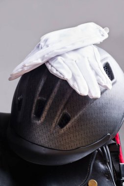 Binici kaskı ve eldivenleri eyere takıldı. Binicilik konsepti. Kapat.