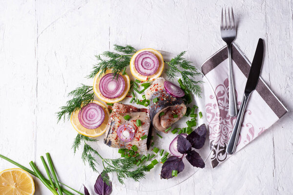 fresh marinated herring roll fillet on a transporant plate with green onion, lemon and seasonings. served in Scandinavian style. Typical cooking fish in Scandinavian countries. 