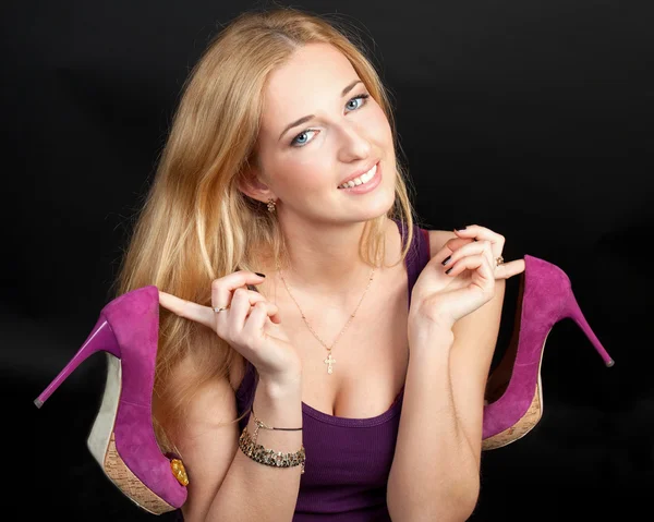 Portret van de mooie jonge blonde vrouw met schoenen in handen — Stockfoto