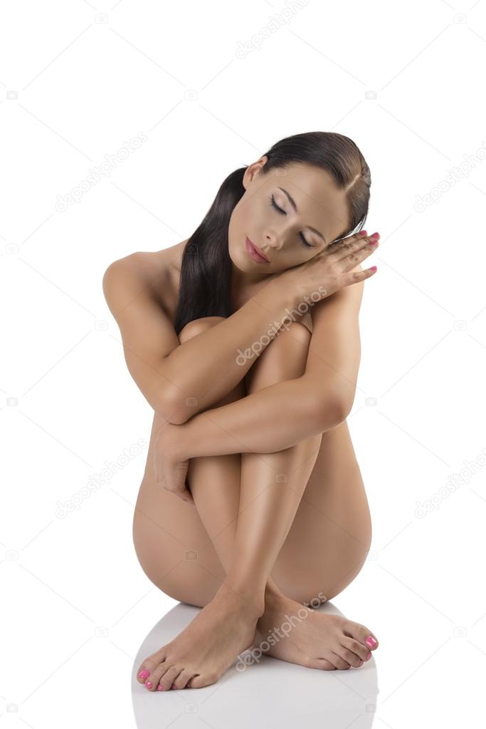 naked brunette sitting on a floor with hand near the face