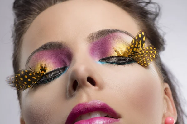 Girl with feathered makeup looks down at left — Stock Photo, Image