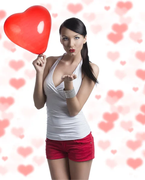 Sexy brunette with heart shaped balloon sends a kiss — Stock Photo, Image