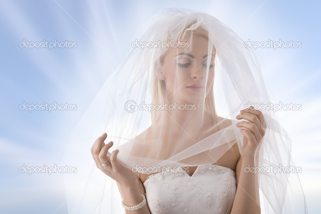 bride with veil on the face looks at left