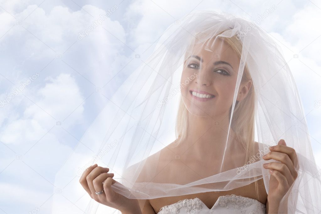 bride with veil on the face smiles