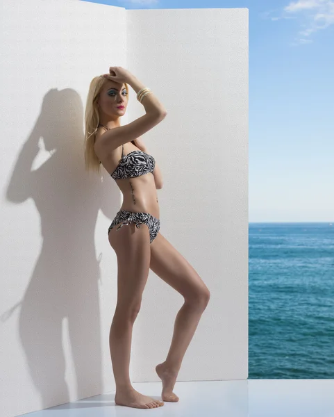 Ragazza bionda in bikini vicino al muro con mano sulla testa — Foto Stock