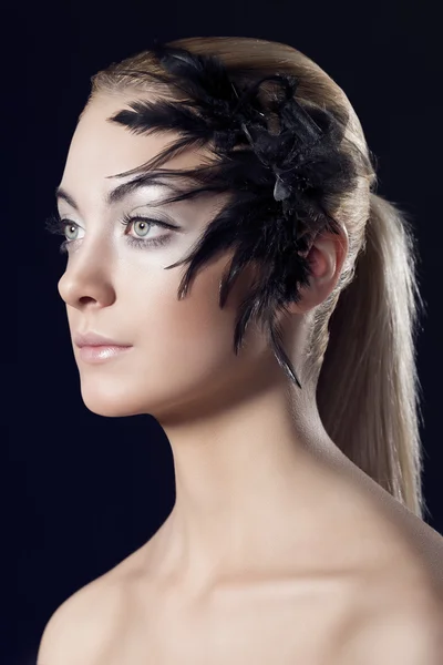 Girl with feathered accessory looks at right — Stock Photo, Image