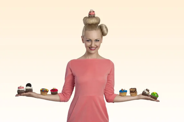 Blonde woman with cupcakes on the arms — Stock Photo, Image