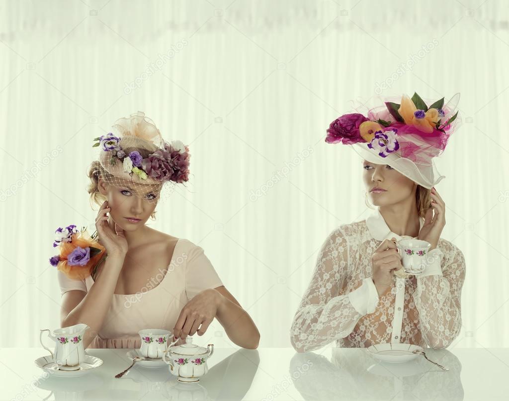 two blonde girl with classical tea set takes tea cup