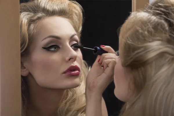Aristokratisches Mädchen trägt Wimperntusche auf Spiegel auf — Stockfoto