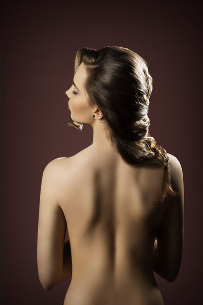 Sensual brunette female showing her base back and creative elegant hair-style