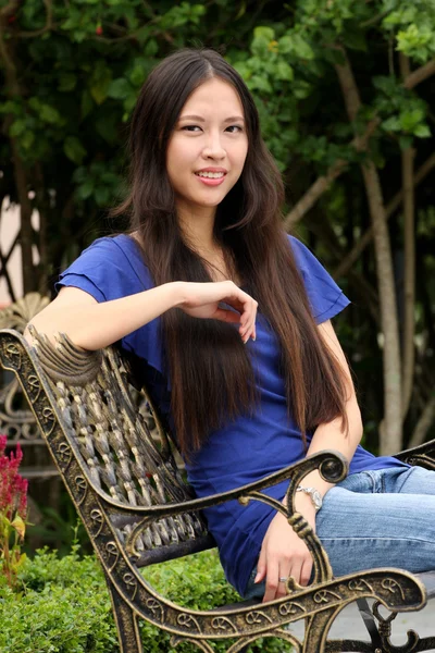 Pretty young woman sitting on the bench in autumn park — Stock Photo, Image