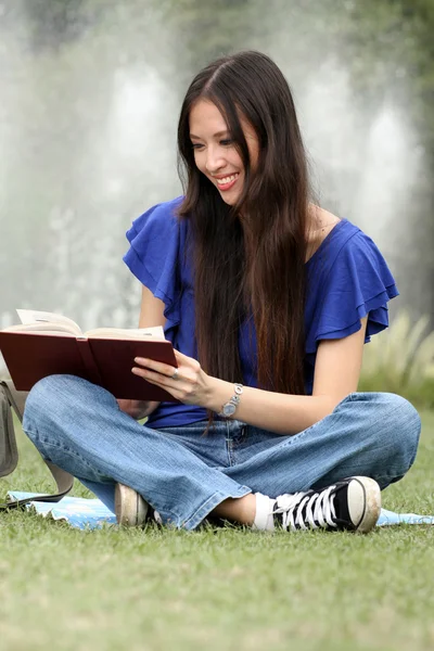 Hübsche junge Frau liest im Park ein Buch — Stockfoto